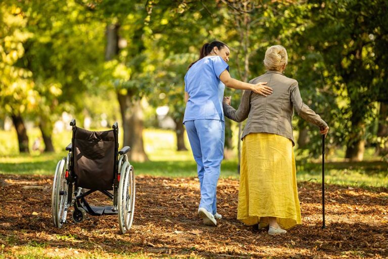 A caregiver assists older adults during an emergency drill in a brightly lit common room.