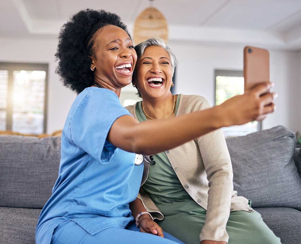 An adult daughter talking gently with her elderly mother in a cozy living room, both seated and holding hands.