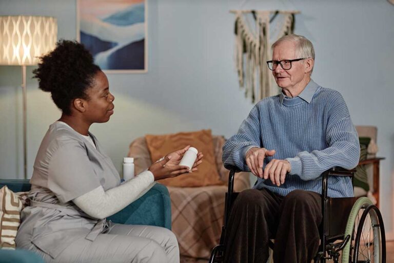 Adult child helps an older relative organize medications at a kitchen table.